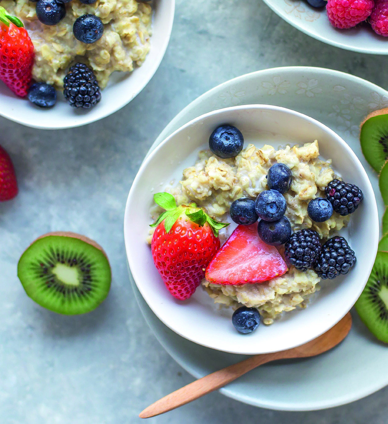 Müslischüssel mit beeren und Kiwi in einer Weißen Schüssel die auf dem Tisch steht
